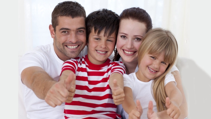 Happy Family Sitting On Sofa With Thumbs Up